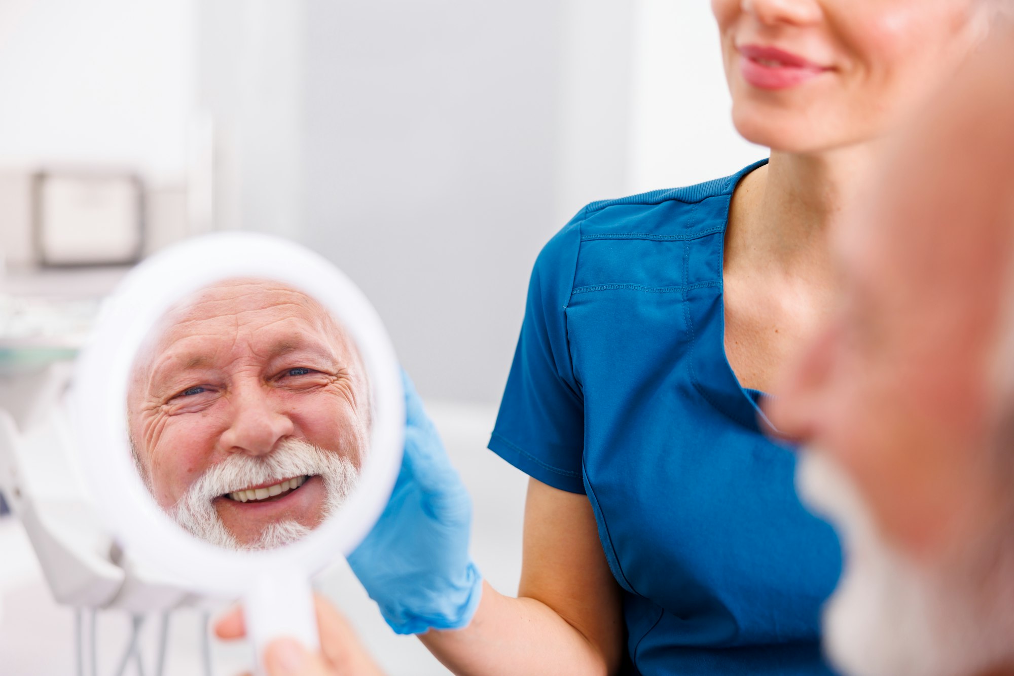 Patient looking in the mirror at dentist office smiling satisfied